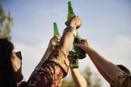 Group of people doing celebratory toast with beer bottles の写真素材