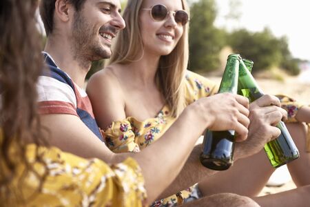 Close up group of friends doing celebratory toast with beer 