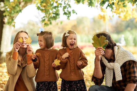 Joyful family having fun with autumnal leaves in woodsの写真素材