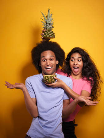 Cheerful Afroamerican couple and tasty pineappleの写真素材