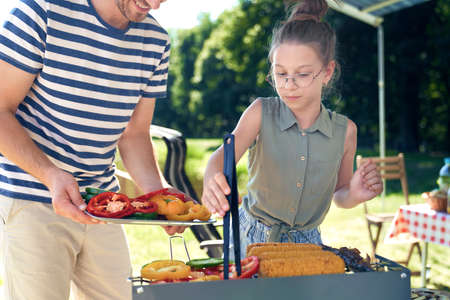 Daughter helping father with barbecue grillの写真素材