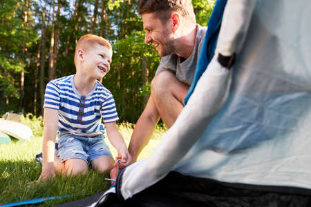 Father and son setting up a tentの写真素材