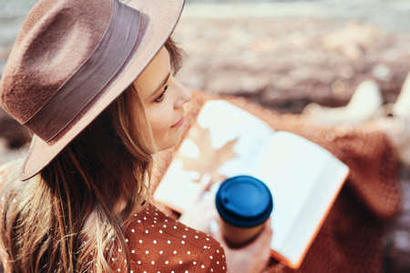 High angle view of woman with coffee and book in forestの写真素材