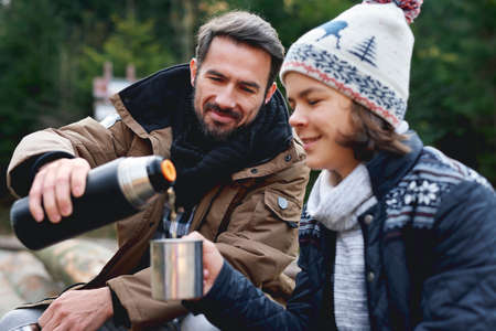 Father and his son drinking tea in the forestの写真素材