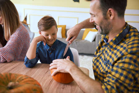 Father helping son in carving pumpkinsの写真素材