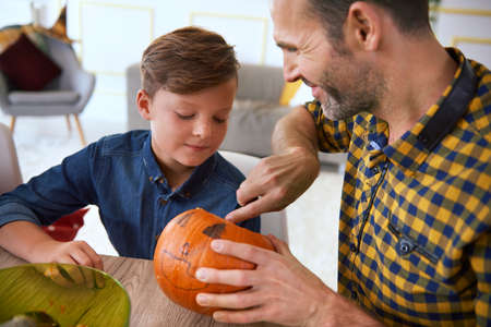 Boy carving pumpkins with father for Halloweenの写真素材