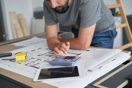 Carpenter calculating something on the calculatorの写真素材