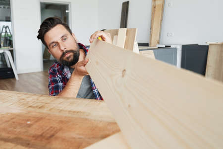 Carpenter looking at a wooden plankの写真素材