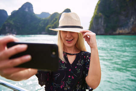 Woman in hat taking a selfie in Ha Long Bay Vietnam
