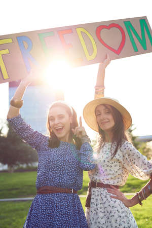 Two happy women standing with a billboard with colored textの写真素材