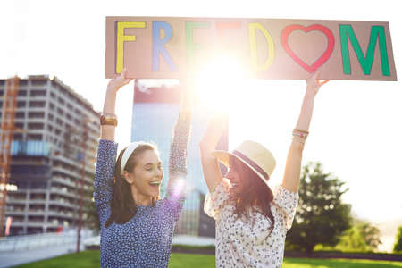 Two happy women with a color billboard looking at himselfの写真素材