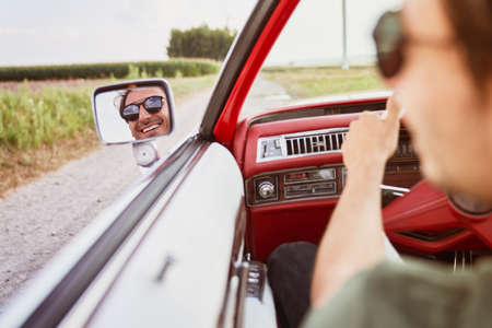 Happy man driving a red vintage carの写真素材