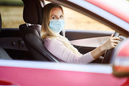 Woman driving a car wearing a protective maskの写真素材