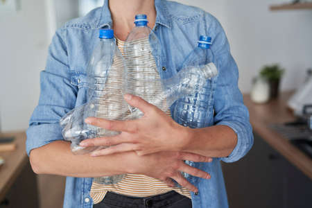 Woman carrying a lot of empty plastic bottles for recycling