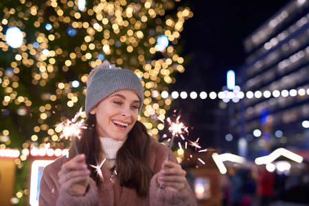 Attractive woman with sparklers on Christmas marketの写真素材