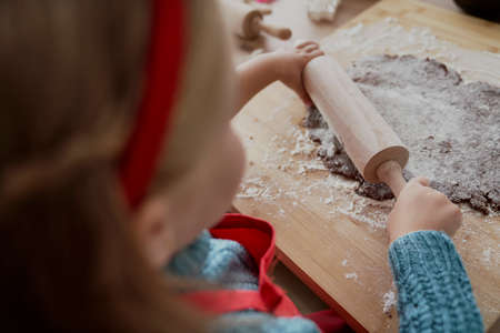 Rear view of little girl rolling gingerbread doughの写真素材