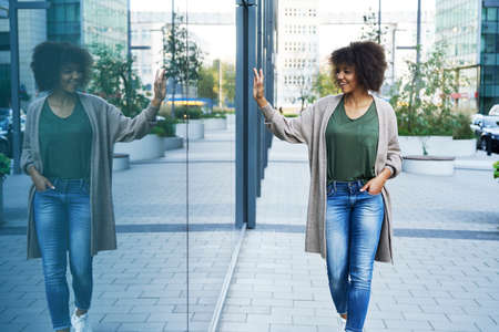 Woman walking outdoors and waving someone through the glass