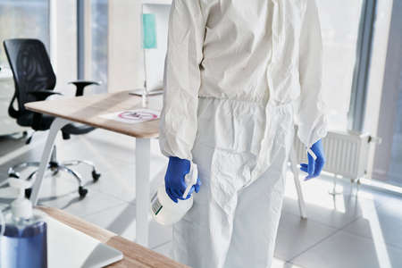 Unrecognizable person in protective workwear with spray bottleの写真素材