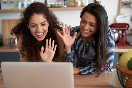 Happy woman waving to someone during a video conference