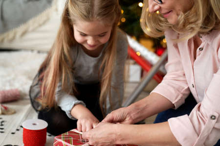 Happy grandmother and girl packing a gift for Christmasの写真素材