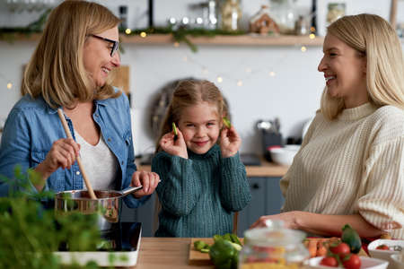 Portrait of little girl playing with cucumber in the kitchen