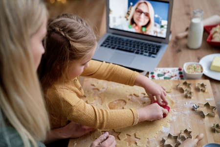 Top view of little girl cutting out cookies from the dough