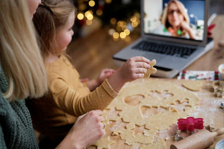 Little girl showing her grandma Christmas cookies during video conferenceの写真素材