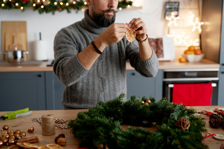 Man decorating Christmas wreath at homeの写真素材