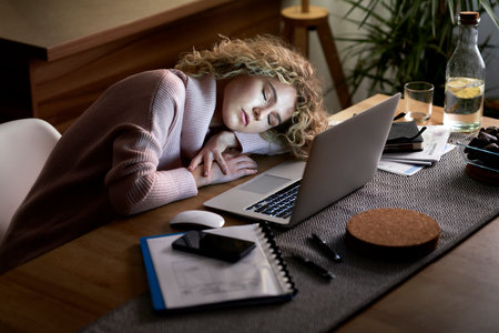 Woman sleeping on the desk in front of the laptopの写真素材