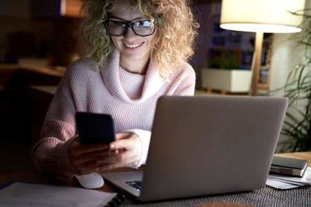 Happy woman working at home in the eveningの写真素材