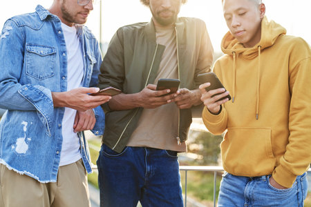 Close up of three young man with mobile phones