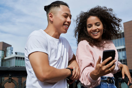 Happy young couple laughing at something while browsing the phoneの写真素材