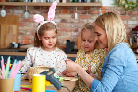 Mom with her daughters preparing Easter decorations at homeの写真素材