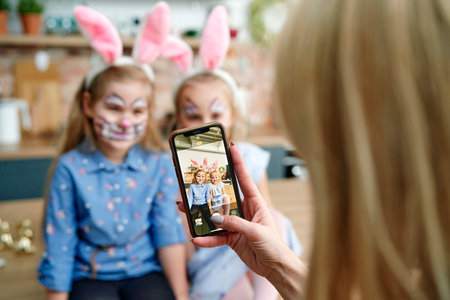 Mother takes photo of daughters dressed up as Easter bunniesの写真素材