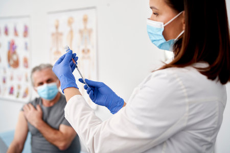 Female doctor preparing syringe for senior patientの写真素材