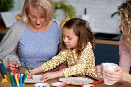 Grandmother and granddaughter painting an Easter rabbits togetherの写真素材