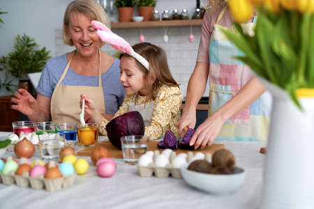 Three generation of women preparation natural dyes for coloring eggs