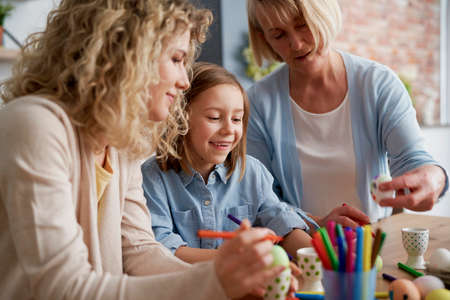 Close up of women decorating Easter eggs at home togetherの写真素材