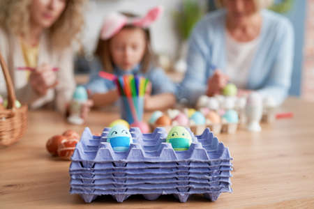 Eggs with face masks on a family background