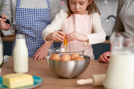 Close up of little girl breaks an egg into the flourの写真素材