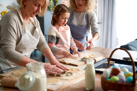 Three generations of women making Eater cookies togetherの写真素材