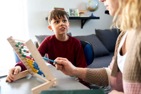 Boy is curious while homeschooling mom teaches using the abacusの写真素材