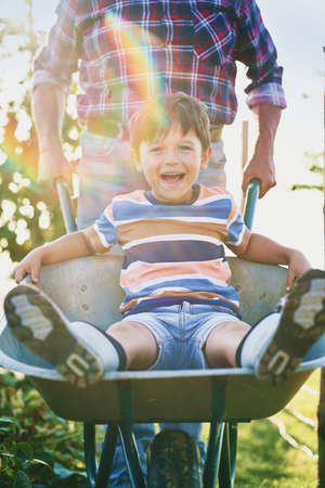 Front view of boy have fun while driving on wheelbarrowsの写真素材
