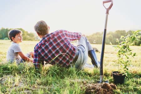 Grandpa and grandson sitting in the meadow at sunsetの写真素材