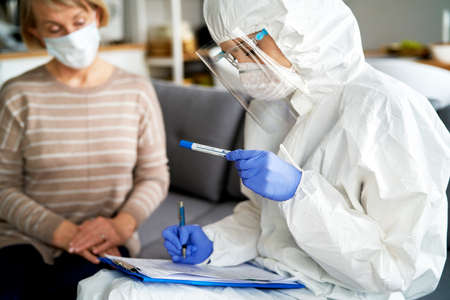 Doctor in protective workwear describing test tube for Covid-19 testの写真素材