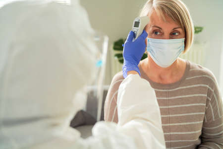 Medical worker measures the temperature of the senior woman