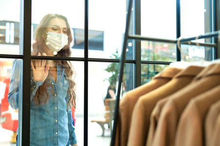 Woman in protective mask admiring window display in shopping mallの写真素材