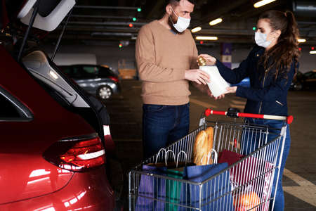 Couple packing their purchases into a car during a pandemic