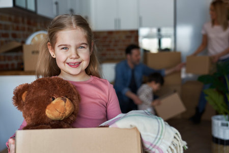 Portrait of little girl holding cardboard box with teddy bearの写真素材