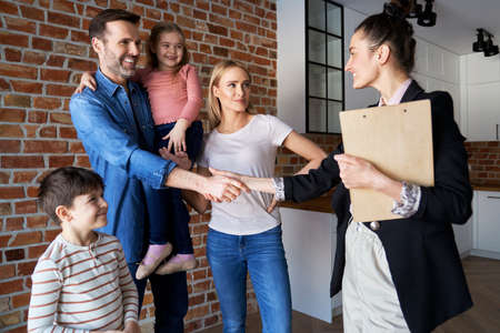 Family shaking hands with real estate agent in new apartmentsの写真素材